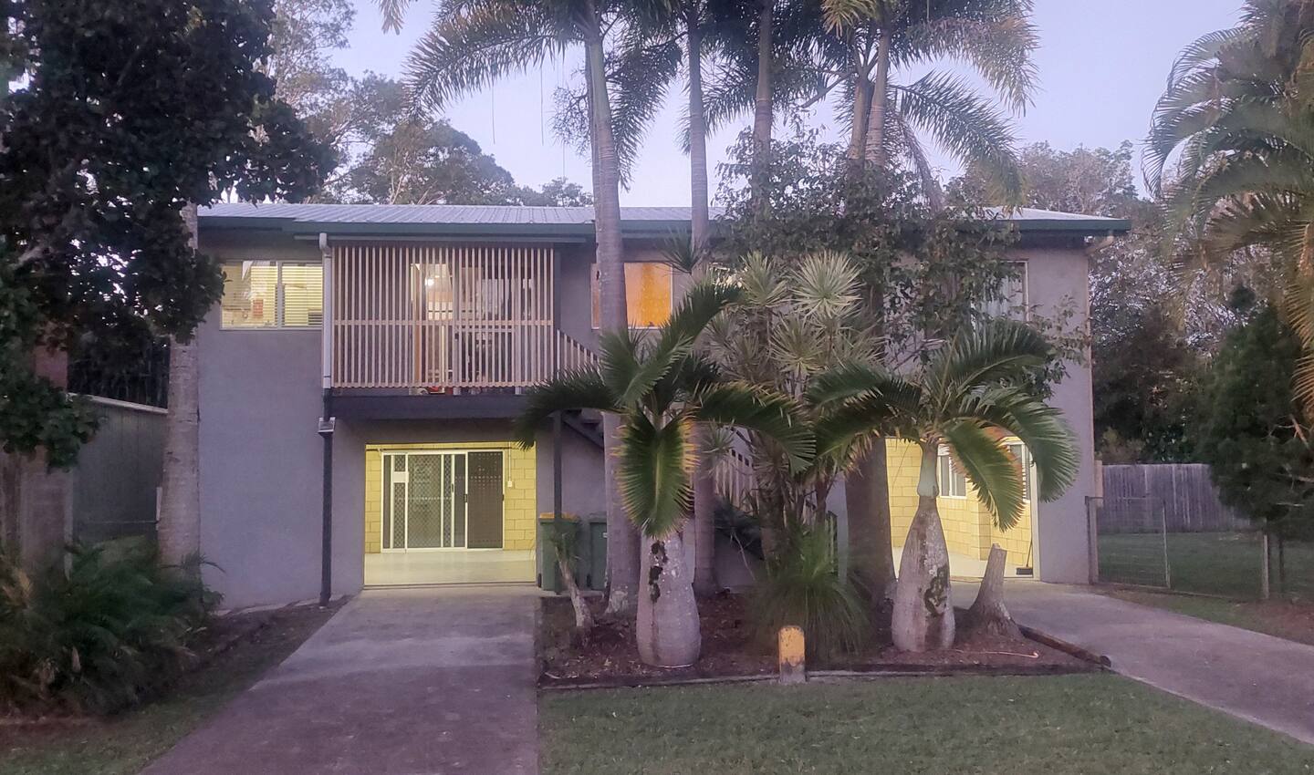 Toolara House at dusk, with palm trees in the front garden